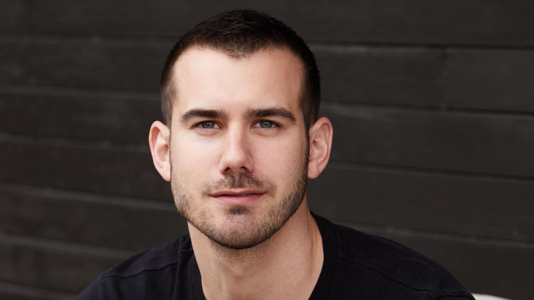 Kevin Gould, entrepreneur and co-founder of Glamnetic and INH Hair, featured in Doc & Glo’s Glo Forward series. Seated casually in a black t-shirt, Kevin gazes confidently at the camera, embodying the focus and calm he shares in his wellness rituals.