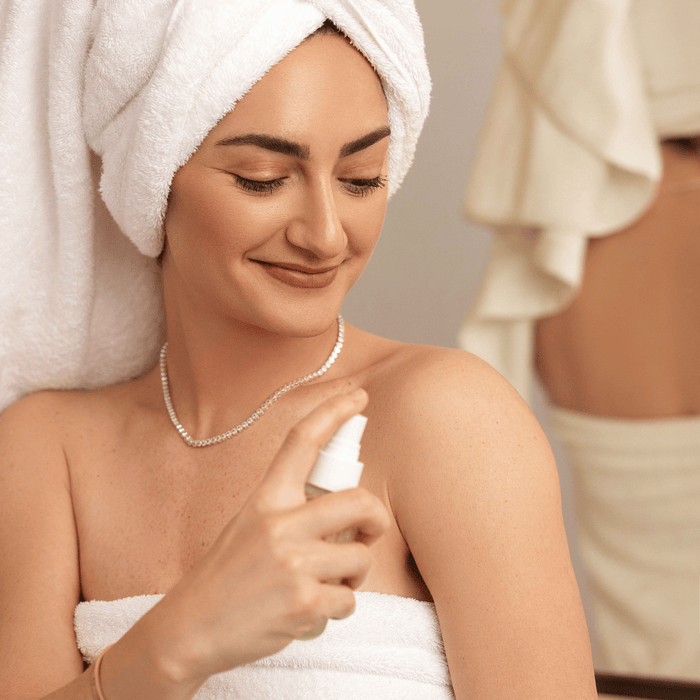 Woman applying 24/7 Hustle mist after a shower